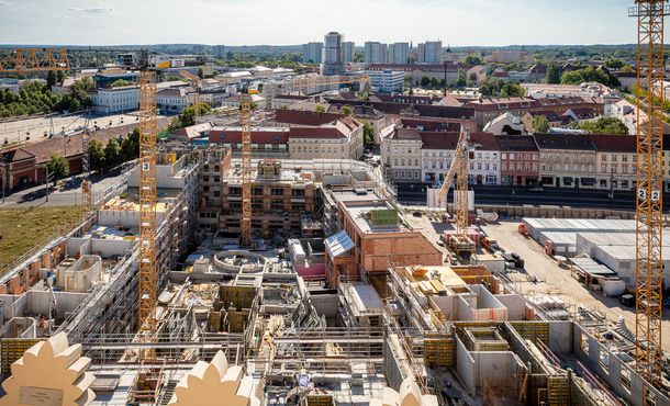 Blick über Baufeld mit unterschiedlich hohen Rohbauten, Kränen und Blick über die Potsdamer Innenstadt